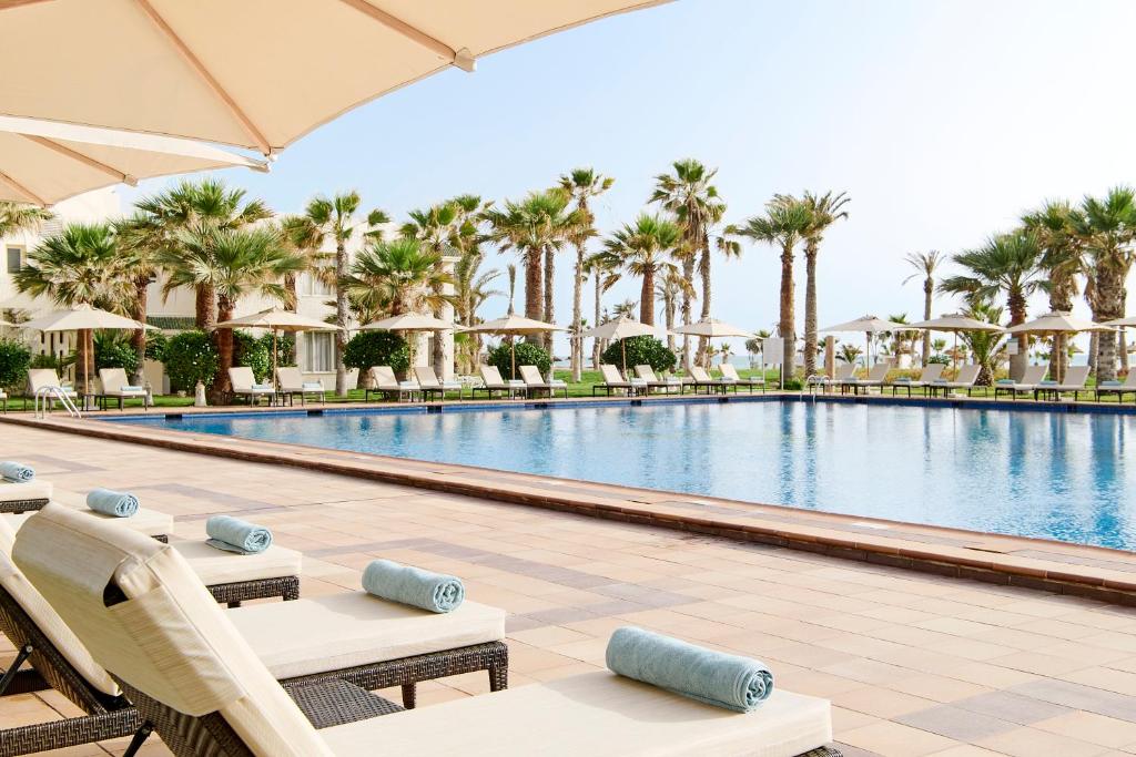 Chaises longues au bord de la piscine avec serviettes roulées et parasols